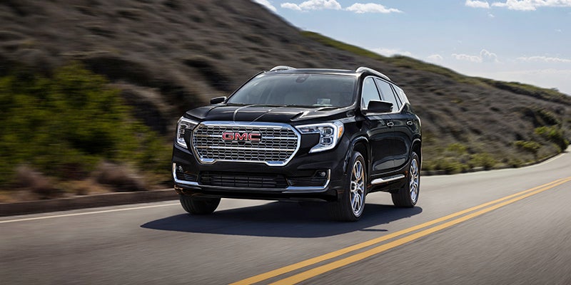 Black 2024 GMC Terrain driving down the highway on a beautiful sunny day
