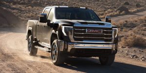 The 2025 GMC Sierra HD driving down a dirt road. 